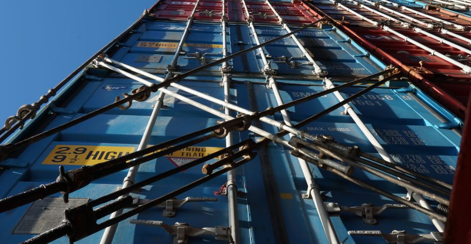 Stack of different colors containers secured on the ship and lashes with lashing bars, turnbuckles and twist locks.