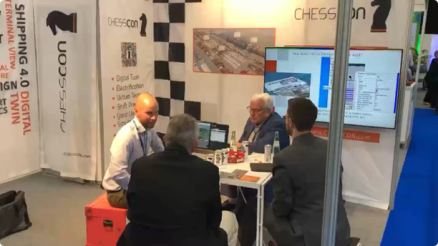 Port colleagues and customers sit around a table at the stand and chat animatedly. The picture shows the lively atmosphere at the Akquinet Port Consulting stand, where the interest in CHESSCON solutions is clear.