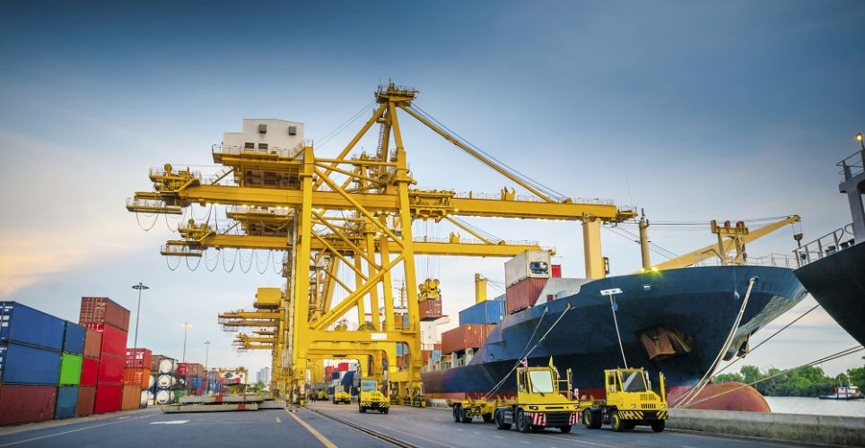 Yellow cranes and terminal tractors. On the left, containers. On the right, a container ship.