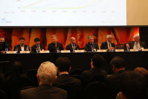 View of the stage with the conference speakers. In the background a presentation with scales.